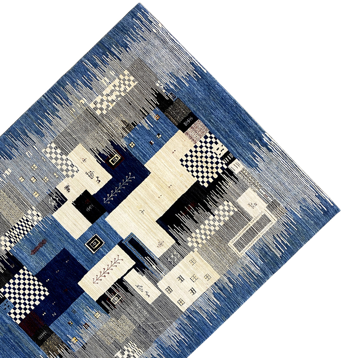 Gabbeh rug detail with patchwork motifs in blue, cream, and black