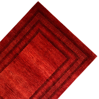 Gabbeh Luri rug with a red central field, multilayered border lines, and fine edge embellishments