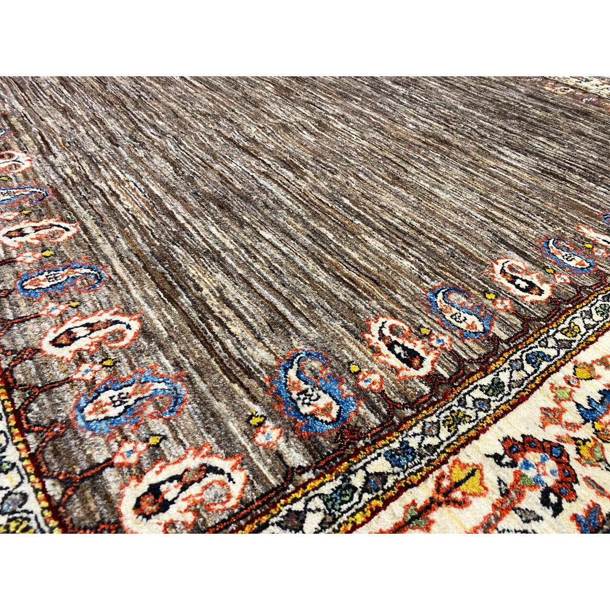 Close-up: brown carpet pile with colorful patterned stripes and ornaments along the edge