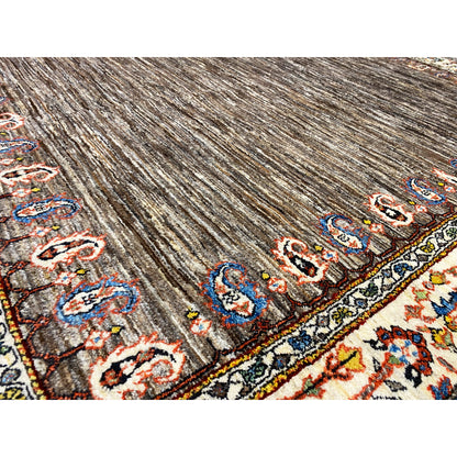 Close-up: brown carpet pile with colorful patterned stripes and ornaments along the edge
