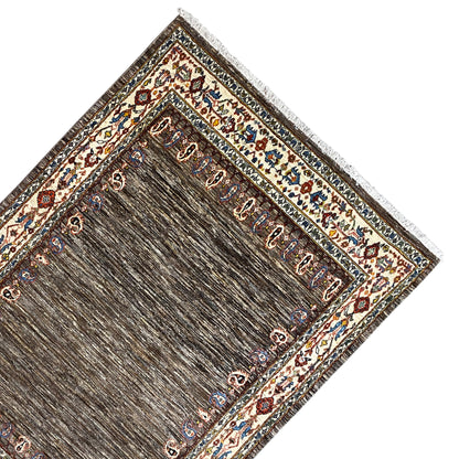 Rug laid out: brown inner field with gold/beige ornaments and finished edges