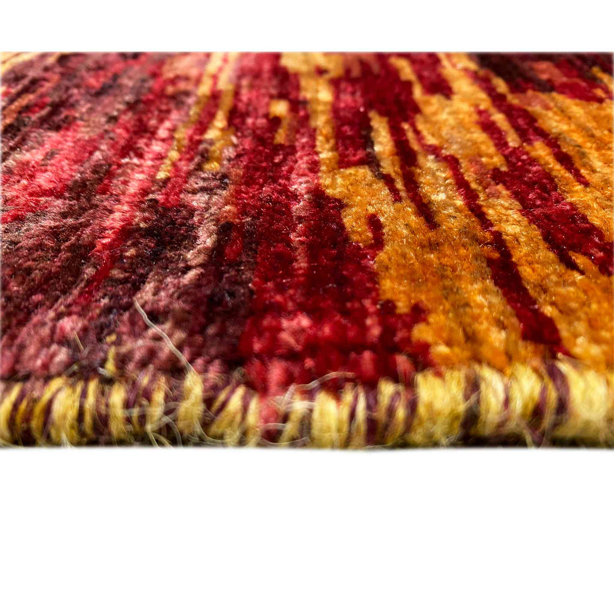 Close-up of a Mamluk rug: colorful patterns and short fringes, rusty brown