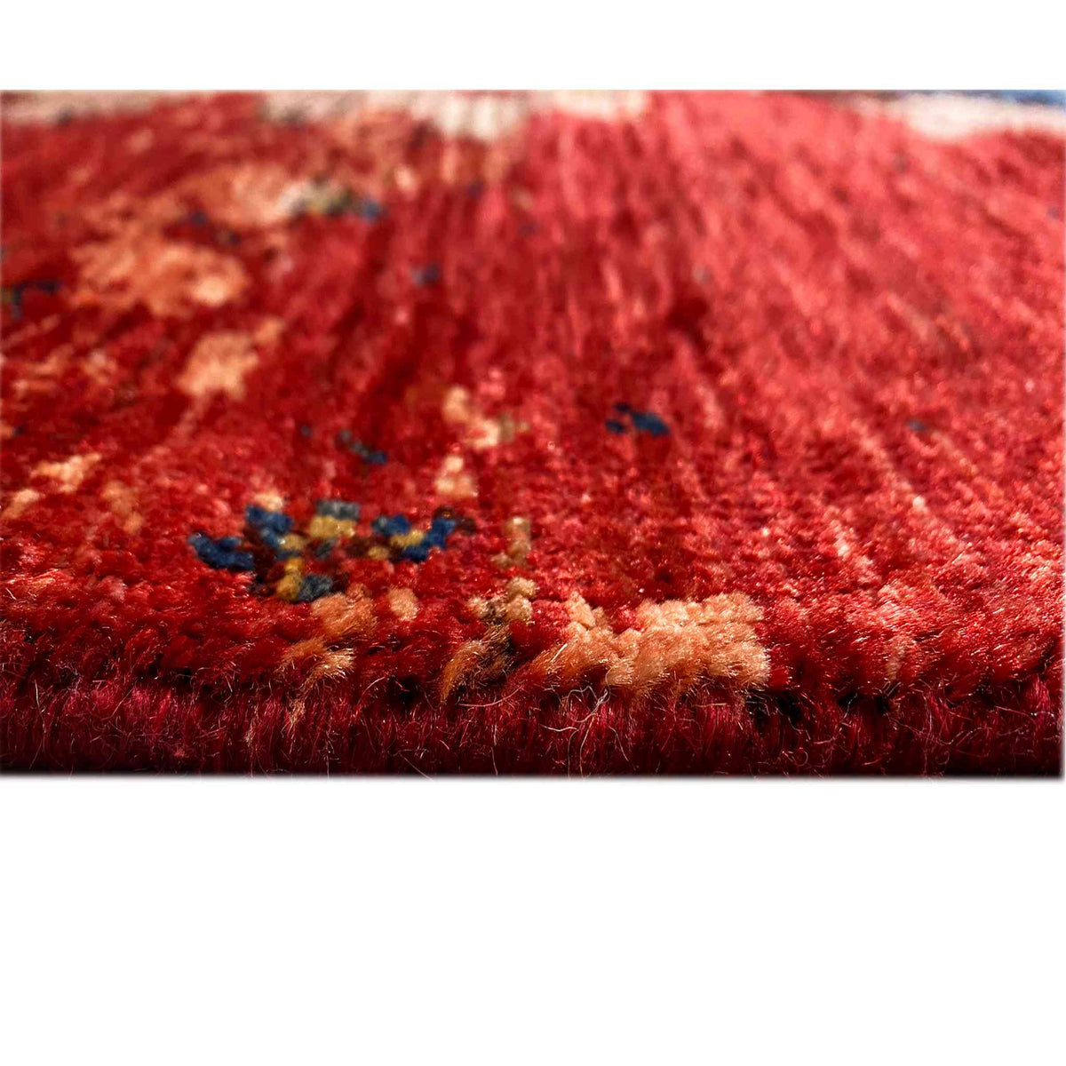 Carpet pile with a red base, visible texture, and small blue-beige patterned areas