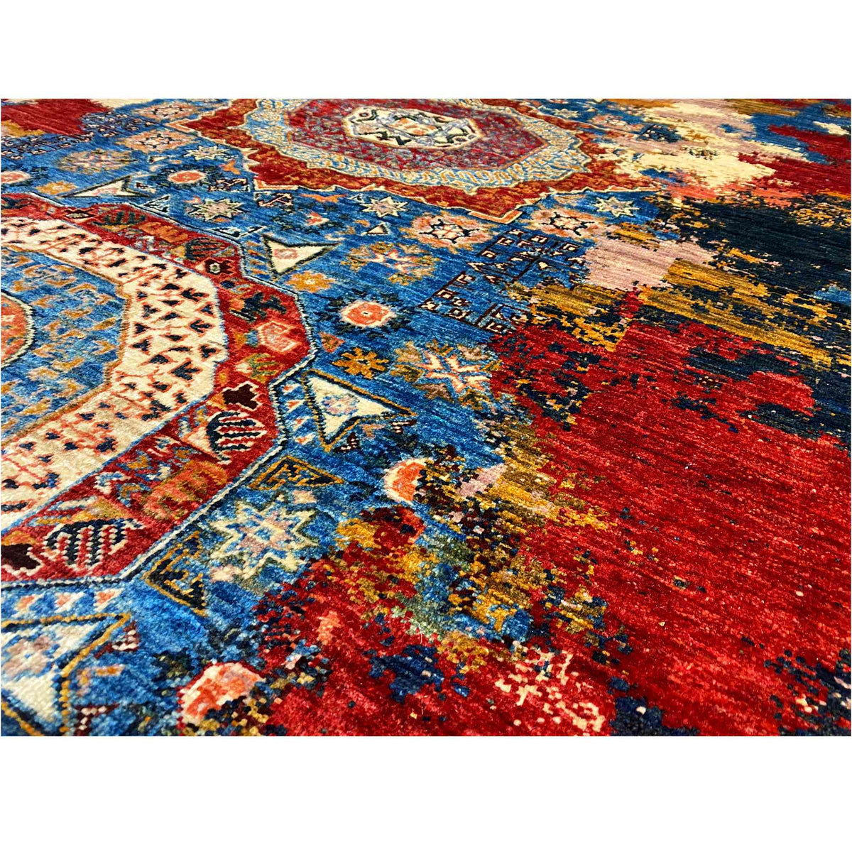 Close-up of a carpet detail with blue ornamental panels, red stripes, and beige accents