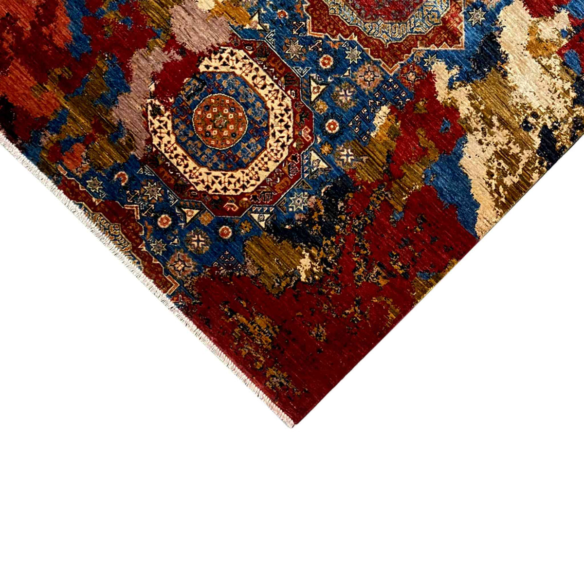 Close-up of the carpet corner: red ornamental field with a blue medallion and beige border edge
