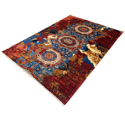 Rug in shades of red, blue, and gold with a central medallion and ornamental corner motifs
