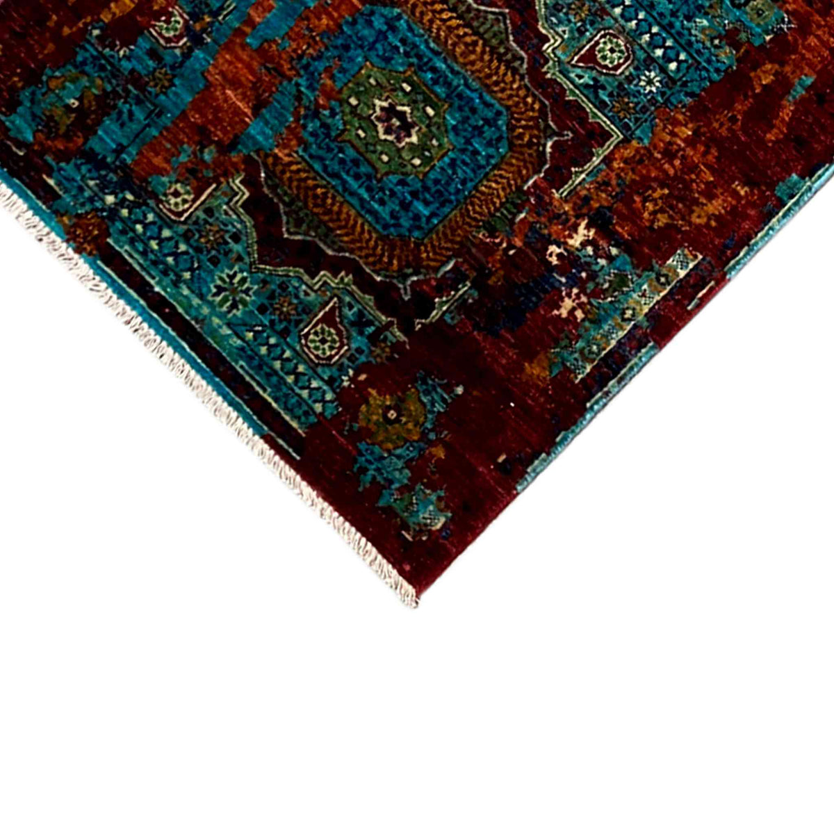 Corner view of runner rug: turquoise pattern on a reddish-brown background, white fringed edge