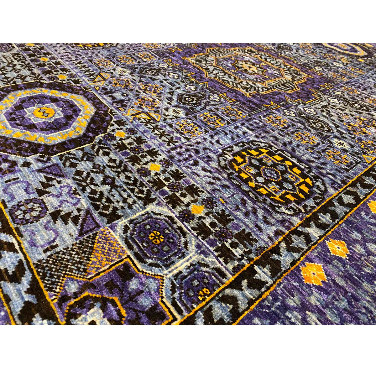 Rug detail: dense pile with a purple pattern, yellow accents, and a dark border