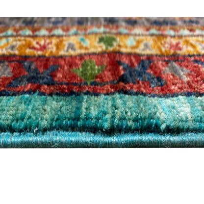 Close-up of the rug edge with fringe; turquoise pile and decorative border