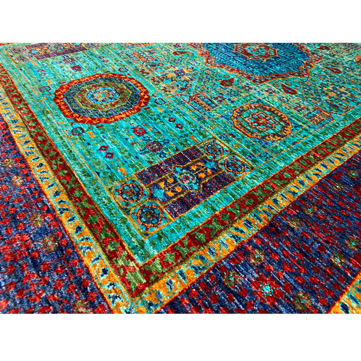 Carpet detail: turquoise pile with medallions, ornaments, and a multicolored border