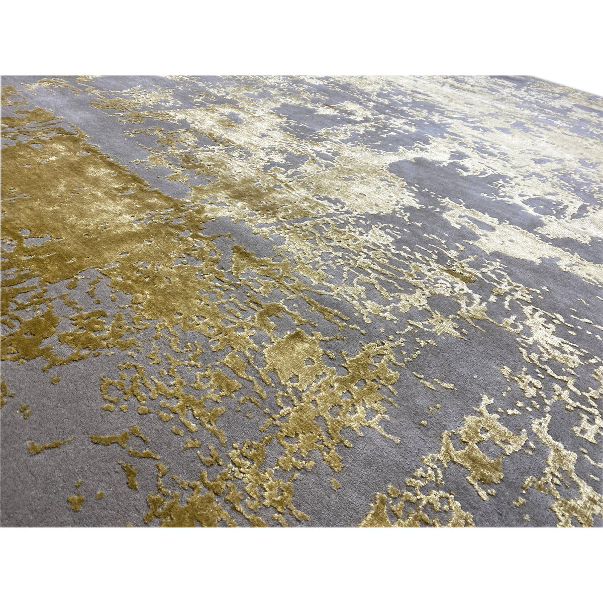 Close-up of a rug: gray-gold, mottled texture with irregular vintage effects.