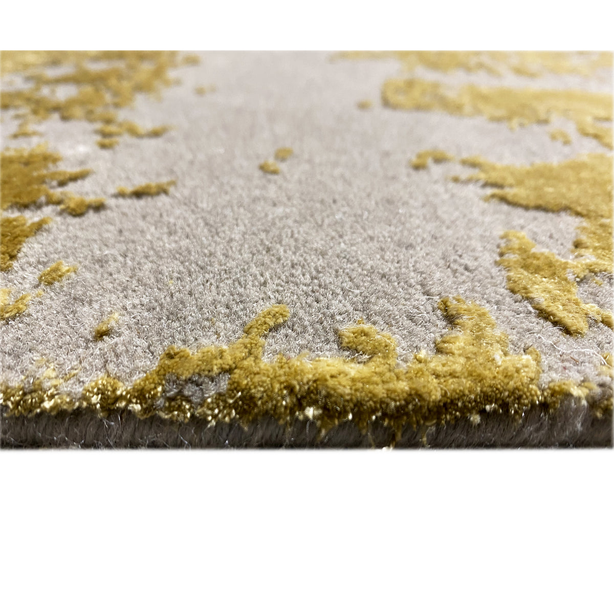 Carpet detail with pile: short, light and golden fibers on a gray surface, right edge visible.
