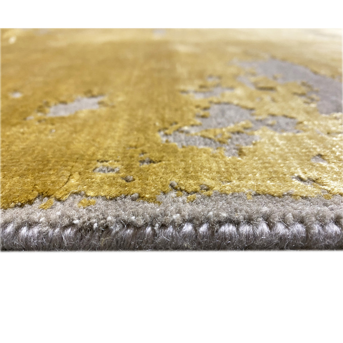 Close-up at the edge: Modern rug with a yellow area and gray pile