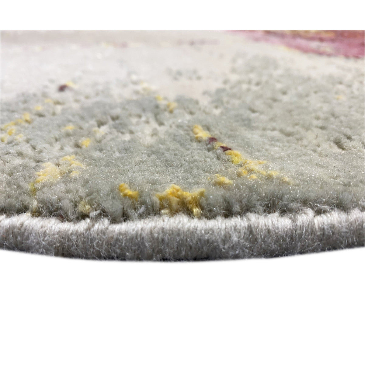 Rug border in the center of the pile, light gray with yellowish accents in the abstract pattern