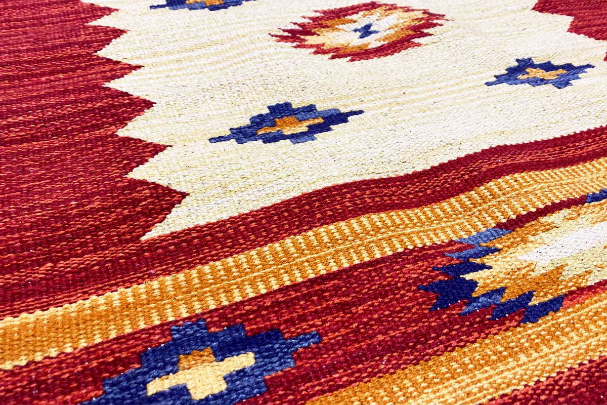 Close-up of a kilim rug, red woven fabric with a beige geometric pattern