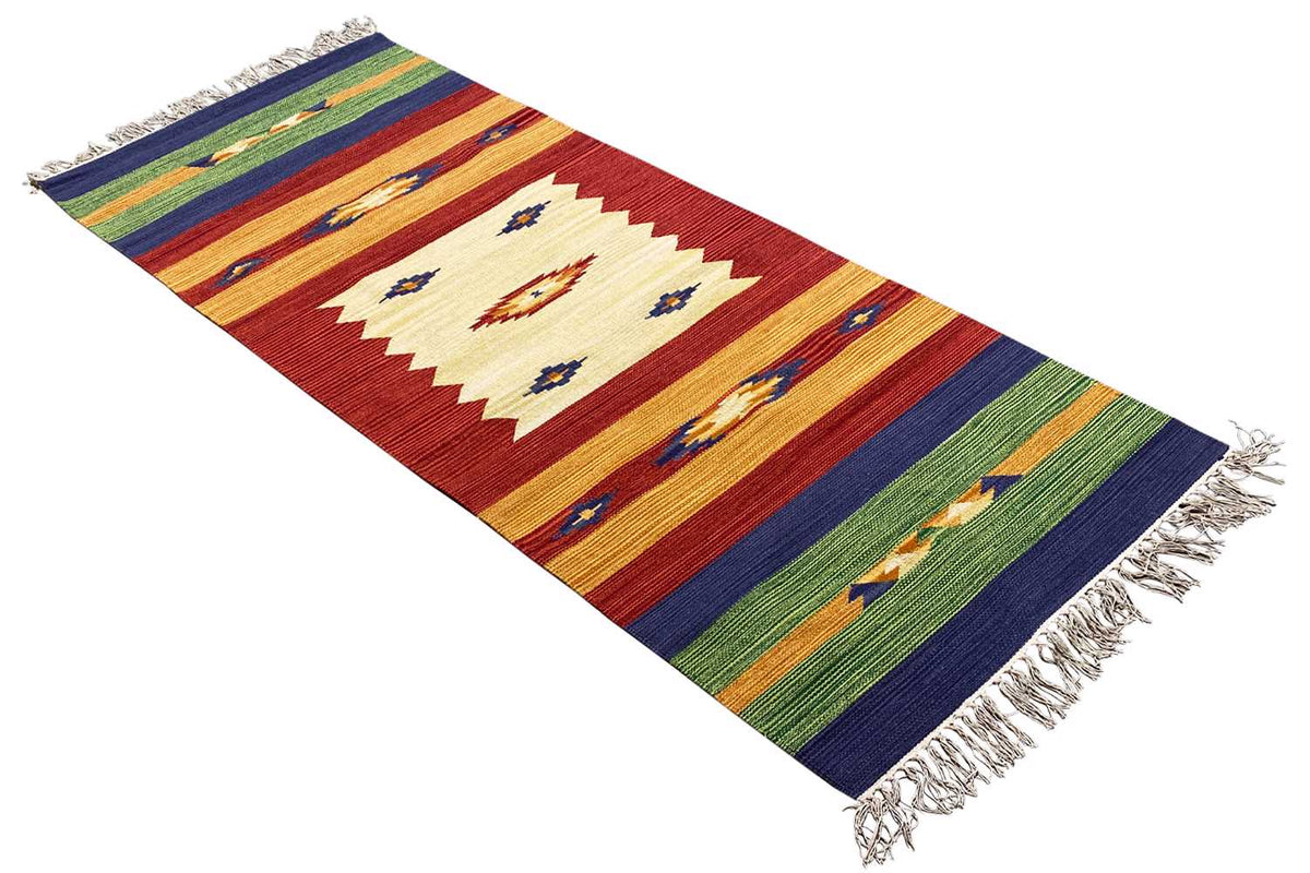 Rug with geometric patterns in shades of red, blue, and green, diagonal view, fringes