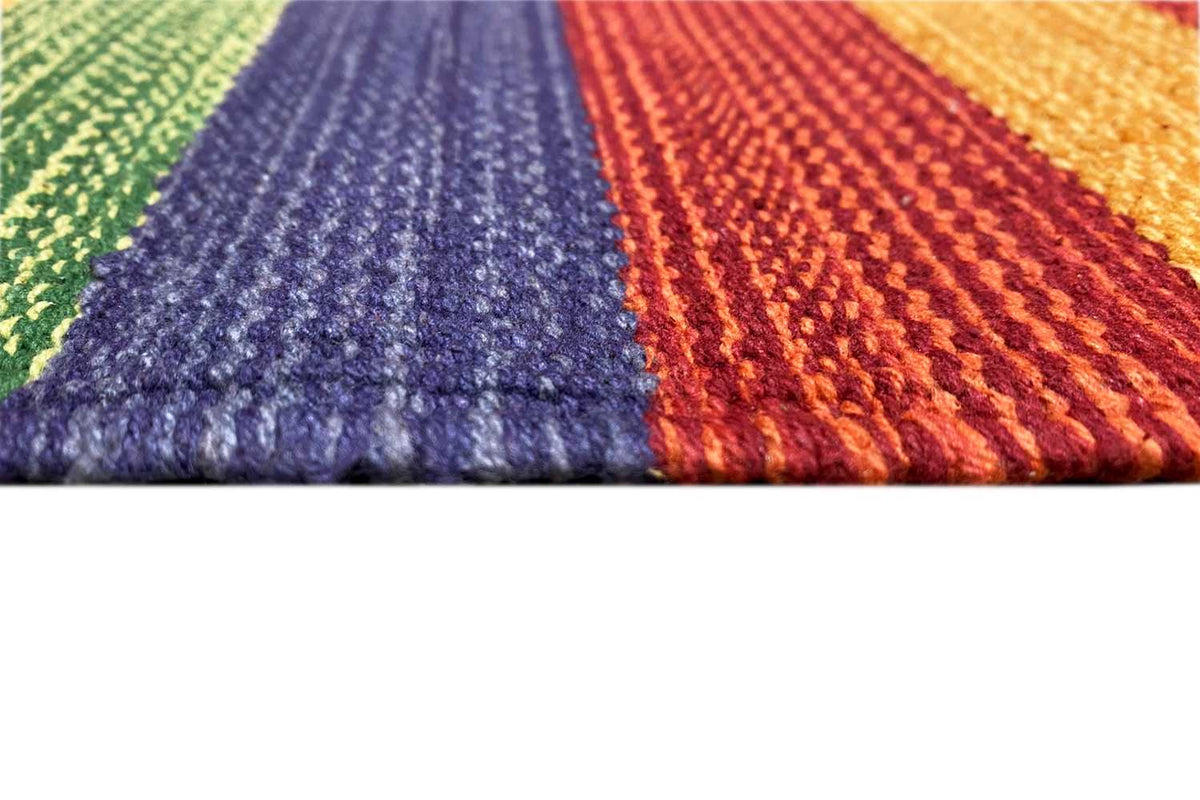 Detailed view of the kilim rug: woven texture in purple, orange, and green with fringed edges