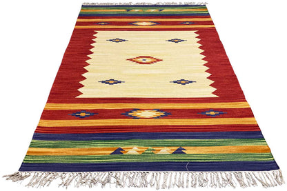 Kelim rug, shown at an angle: red and beige base with squares, stripes, and fringes