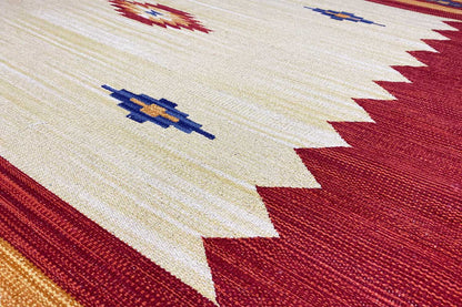 Kilim rug detail: beige pile with a red border, geometric blue shapes, and texture