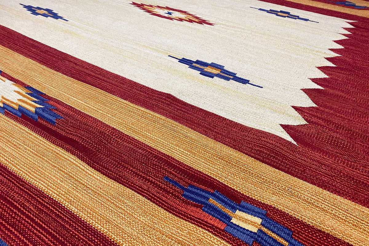 Close-up: kilim threads with warm red and ochre stripes as well as blue pattern lines