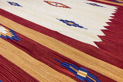 Close-up: kilim threads with warm red and ochre stripes as well as blue pattern lines