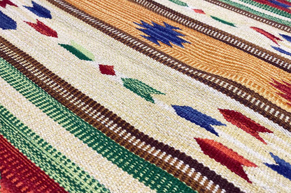Kilim rug detail with blue, red, and green ornaments on a beige background.