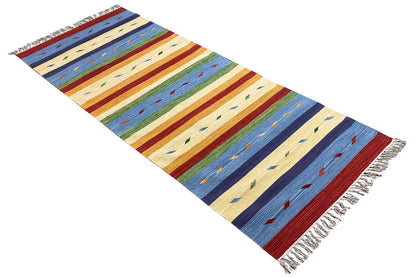 Modern kilim rug spread diagonally: multicolored stripes, subtle patterns; fringed edge.