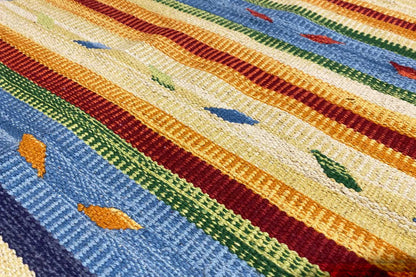 Close-up of a kilim rug: knitted texture with colorful stripes and small geometric motifs.