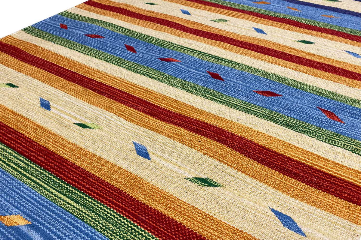 Close-up of a kilim rug with a woven texture, multicolored stripes, and dotted elements