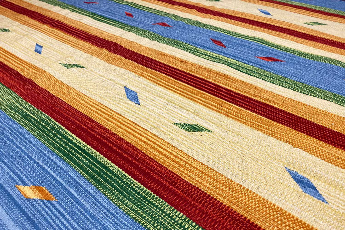 Kilim rug with wide stripes and diamond patterns in blue, beige, red, and green.