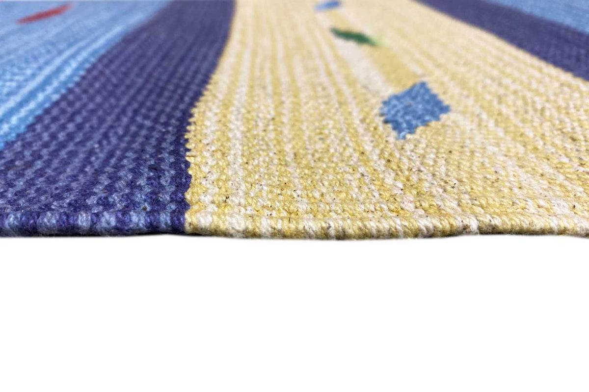 Close-up of the kilim rug: textured woven surface with stripes in blue and beige; pile visible.