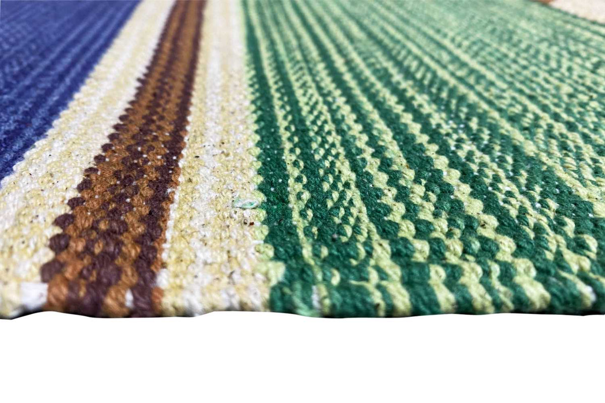 Detail of a kilim runner rug: green and blue woven texture, patterned stripe