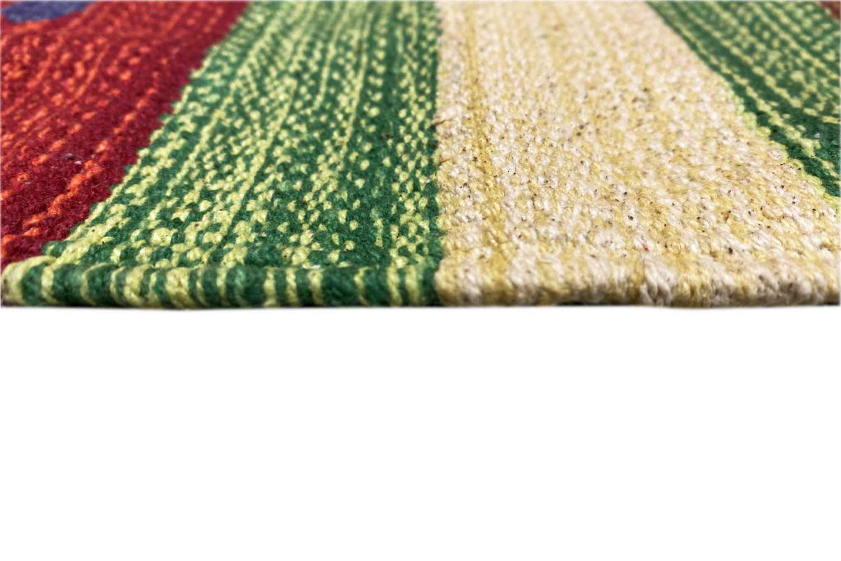 Close-up of the kilim rug: braided texture with stripes in green, red, and cream, fringes