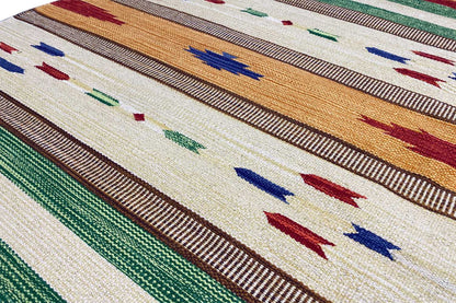 Detail of the kilim rug: thin stripes and dots in cream, green, blue, and red, visible woven texture