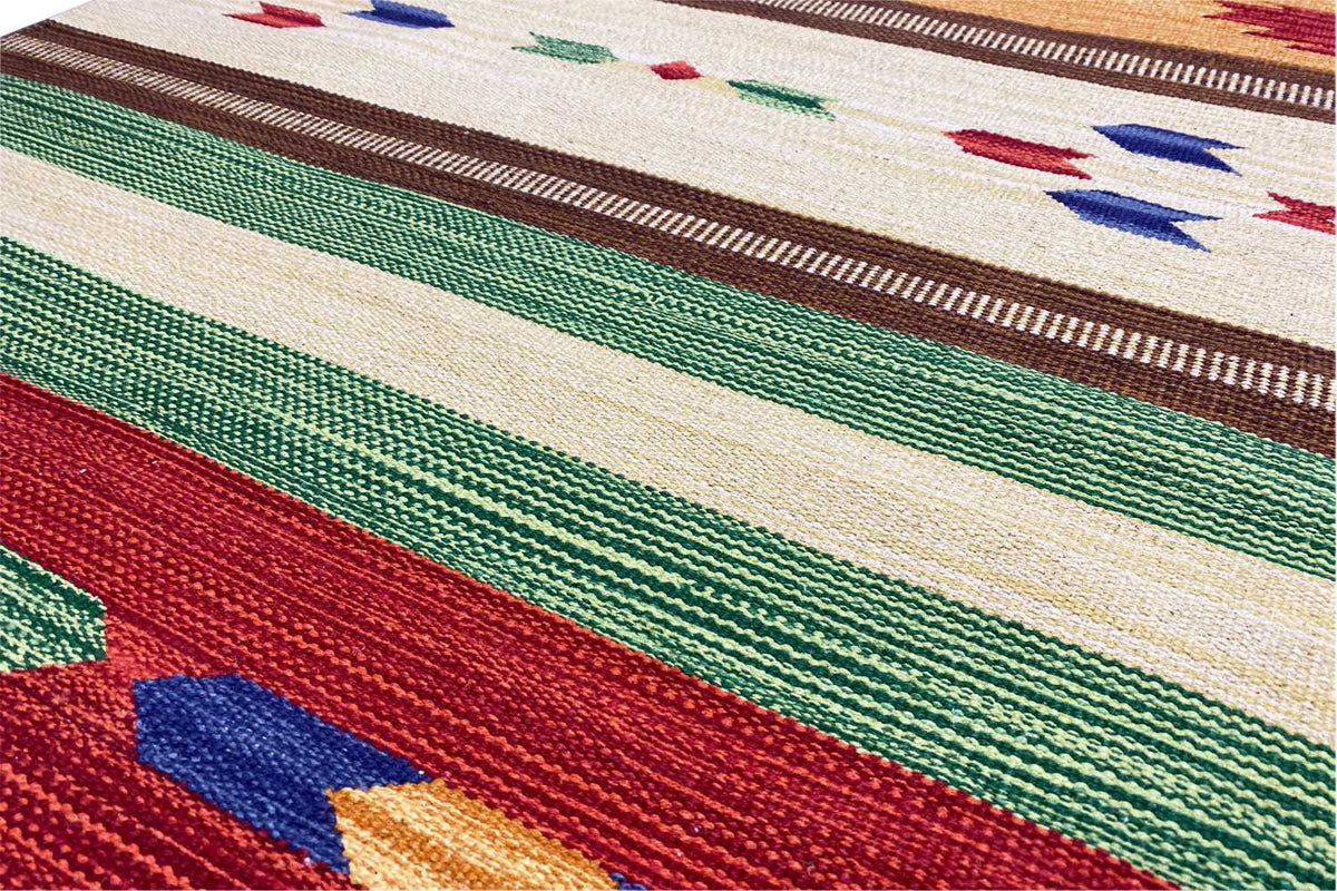 Close-up of a kilim rug: woven texture with diamond shapes, stripes in red, green, blue, and beige
