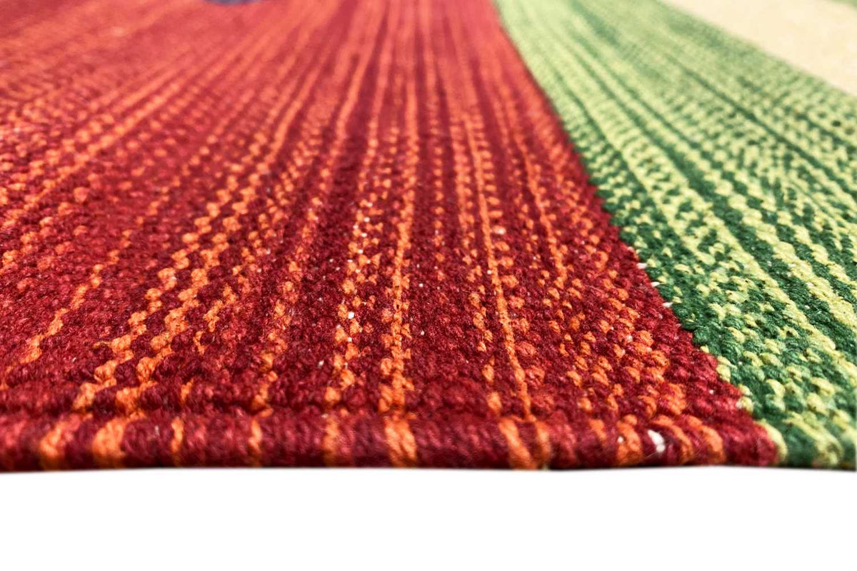 Textile detail on the kilim rug: reddish-green pile with a dense, patterned weave structure