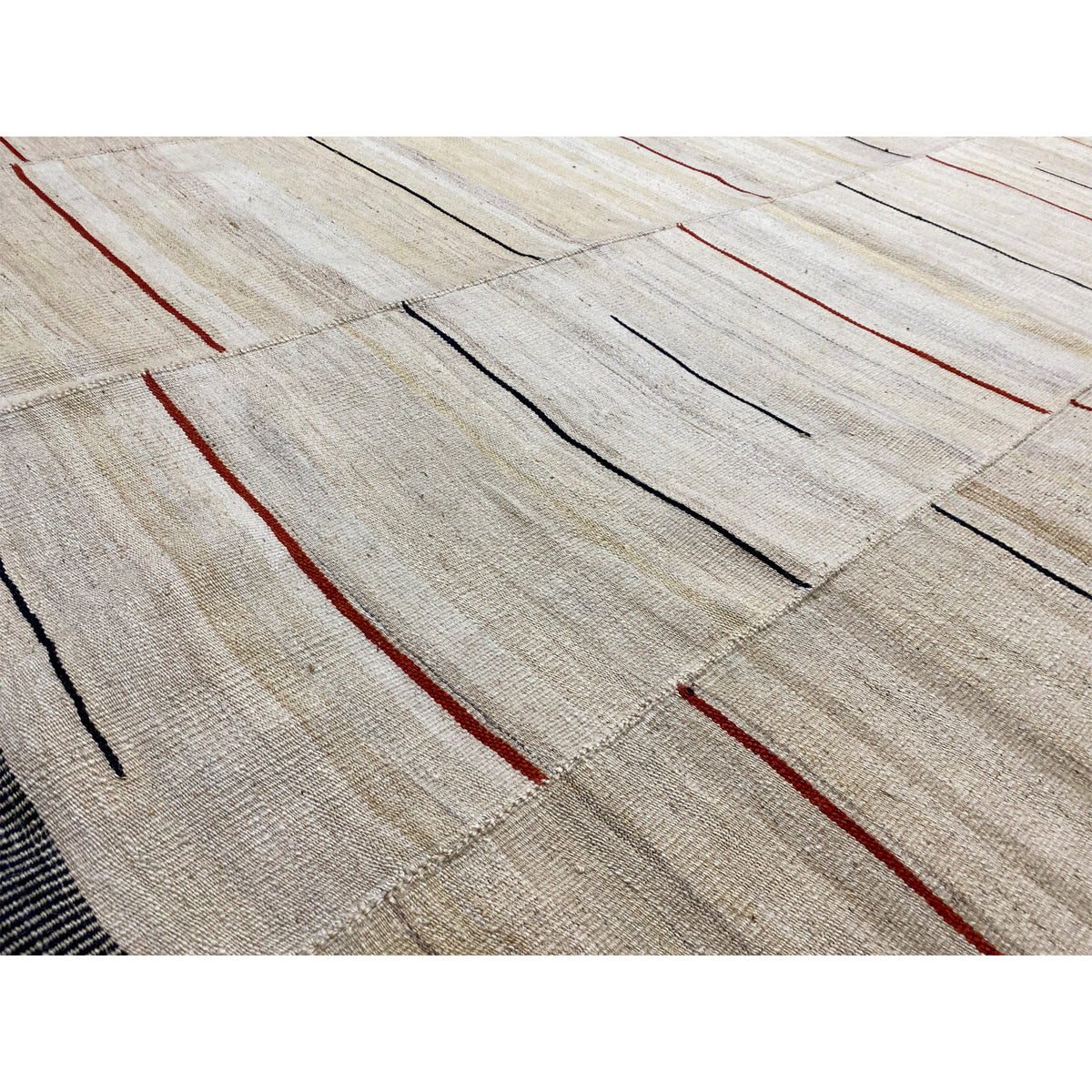 Detailed view: beige kilim with narrow horizontal stripes, red accents, and a dark border