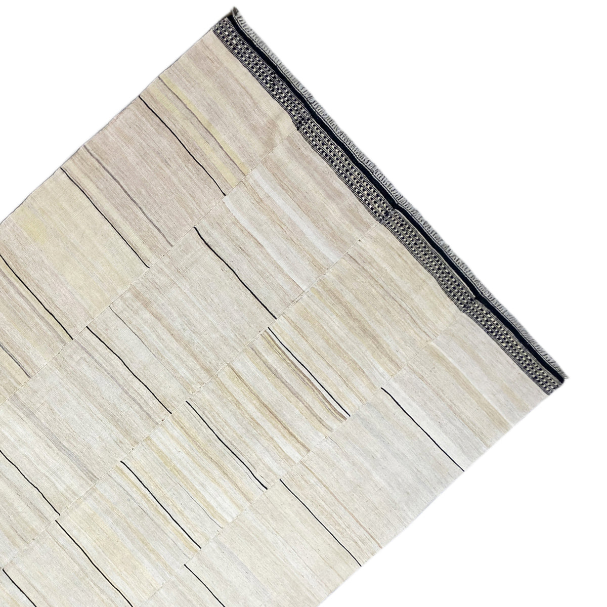 Corner of the kilim rug with a cream-colored pattern and dark gray border trim