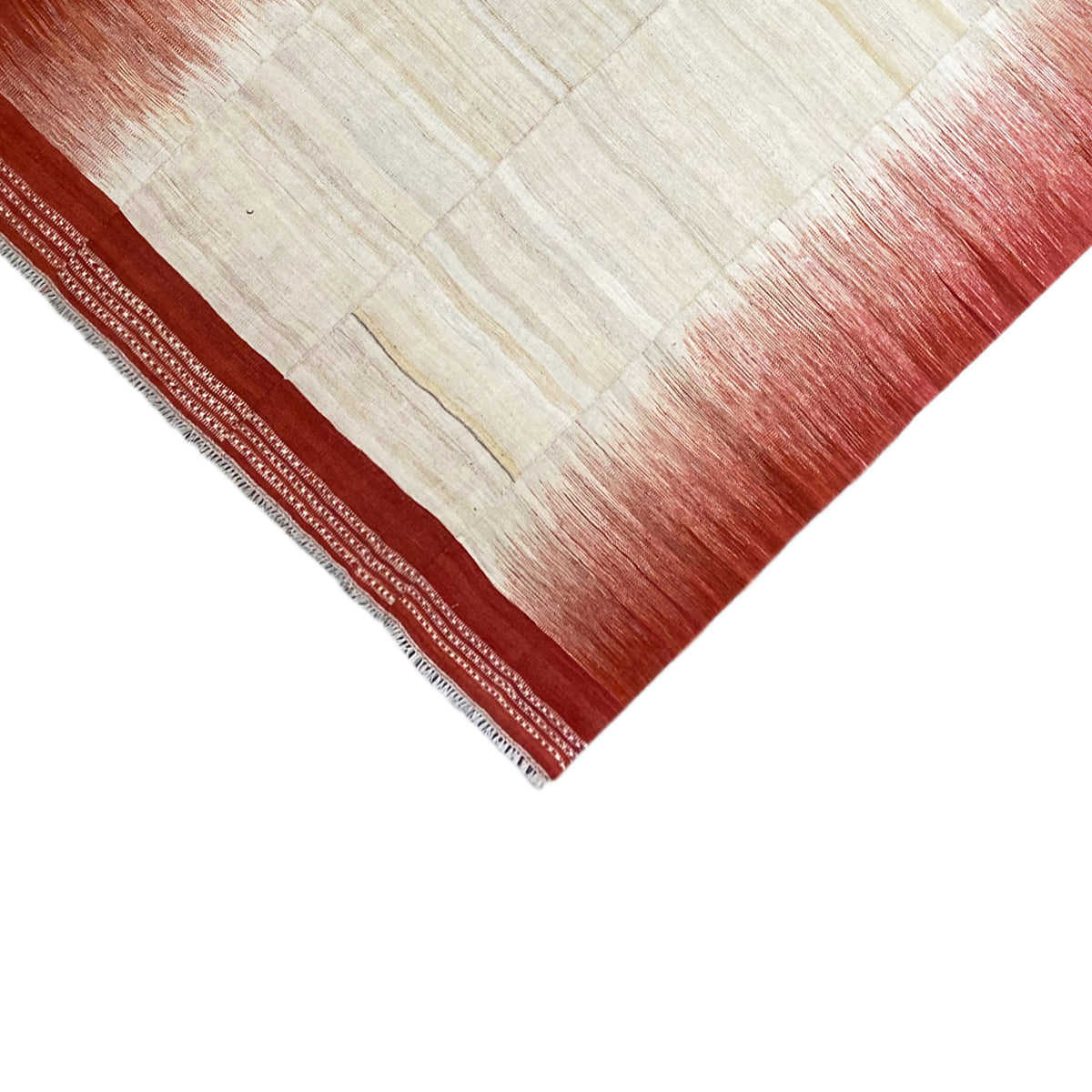 Close-up of the kilim corner: cream-white square pattern, reddish-brown field edges, and a mult-line border