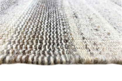 Close-up of the carpet edge with a dense woven pattern in gray and beige