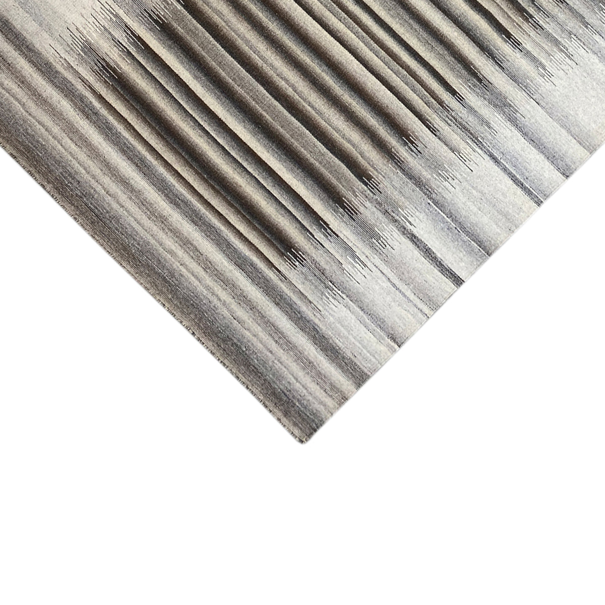Corner area of the gray rug with stripes and fine edge finishing