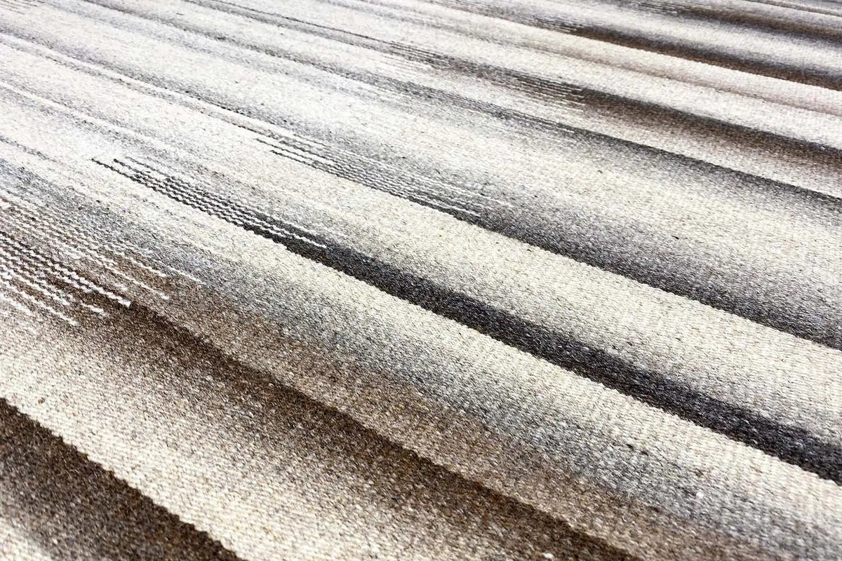 Close-up of carpet surface: striped pattern in light beige, gray, and dark brown