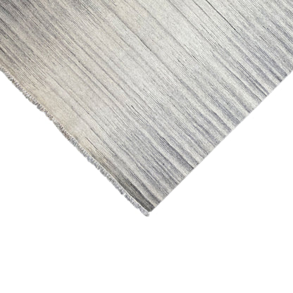 Kelim dhurrie rug detail with light and dark stripes, fringe at the corner