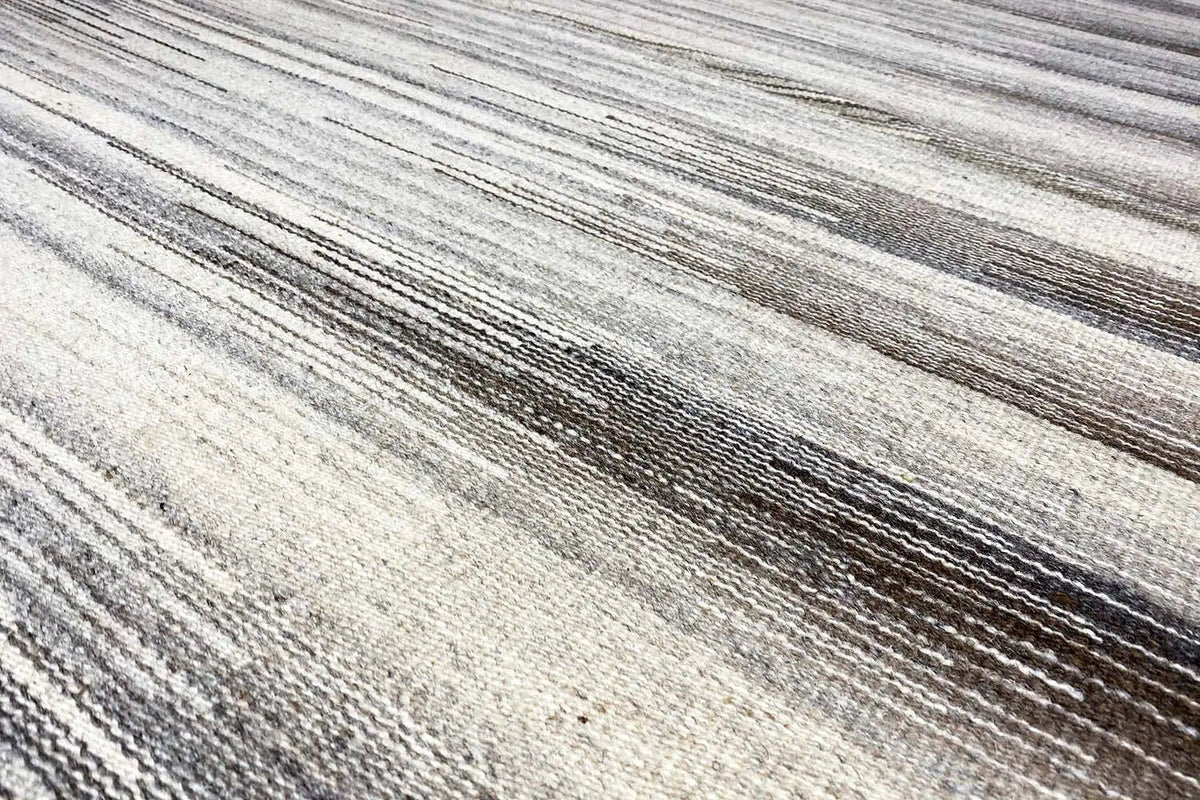 Close-up of the stripes in the kilim rug: beige and gray-brown linear pattern