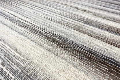 Close-up of the stripes in the kilim rug: beige and gray-brown linear pattern