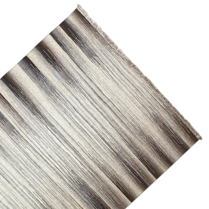 Close-up of a kilim rug: fringed edge, striped beige and dark gray
