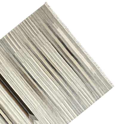 Border area of a kilim dhurrie rug with a bound edge and stripes in gray and beige