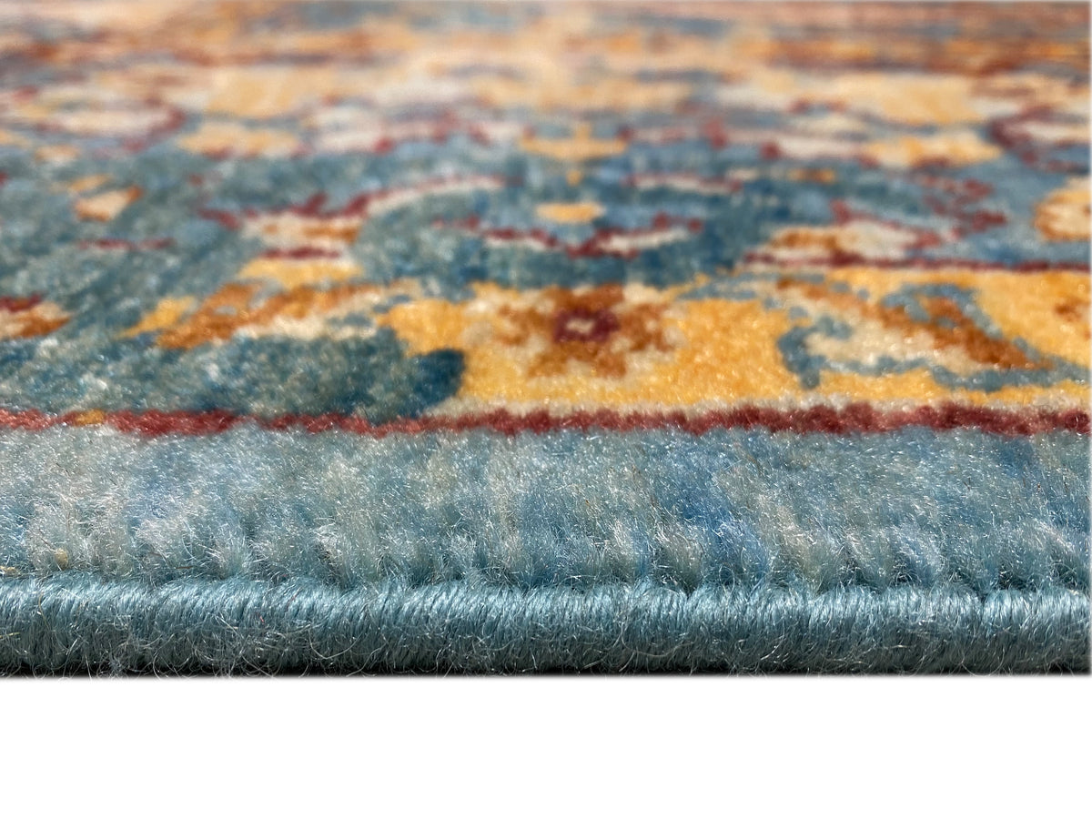 Nahaufnahme: Teppichoberfläche mit blauem Flor, aufgeprägten Mustern und mehrfarbiger Kante