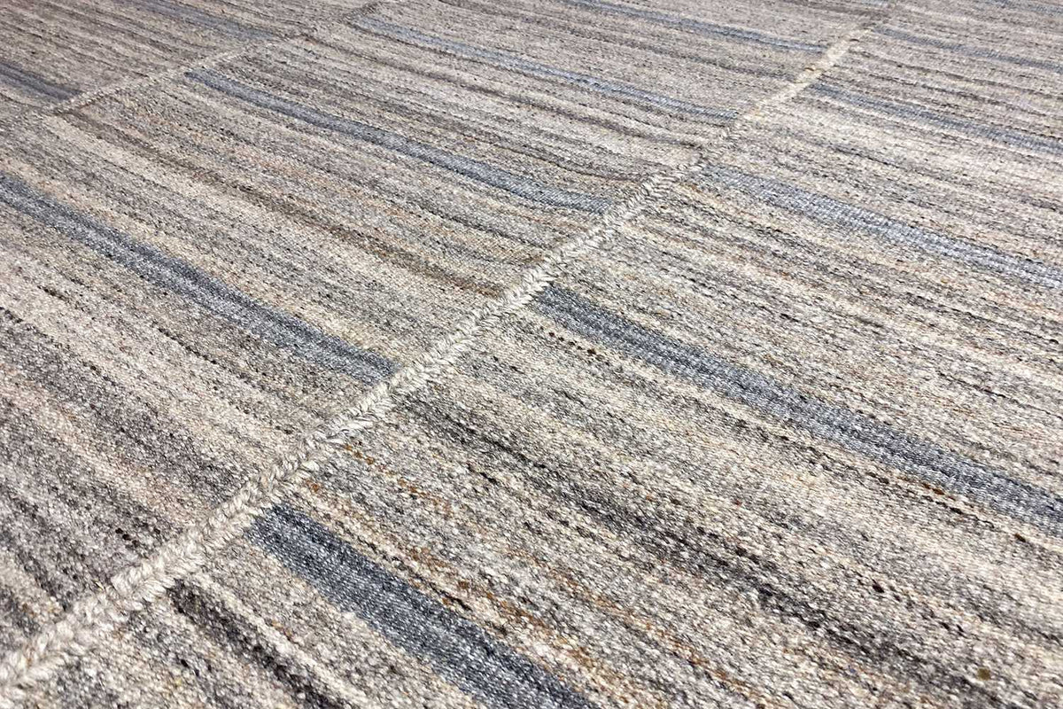 Close-up of a kilim rug: woven patterns with cross and stripe lines in gray/blue