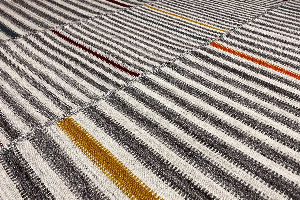 Close-up of the kilim weave pattern: gray stripes with yellow-orange and red accents
